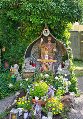 Wunderschöne üppig dekorierte Grabstätte mit der Jesusfigur unter einem Dach auf dem Waldfriedhof in Memmingen © Blende8