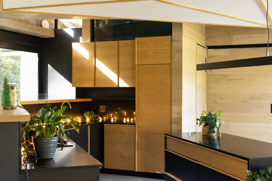Wood cabinets and black counters showing kitchen island with under-cabinet fairy lights and pendant