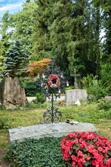 sehr schönes altes Eisenkreuz mit schöner Dekoration und einem Kranz auf dem Waldfriedhof Memmingen © Blende8