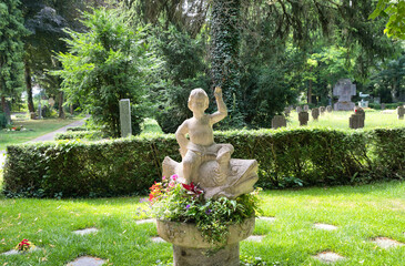 Urnengrabfläche mit einem schönen Mittelpunkt ein Knabe auf einem Fisch  auf dem Walfriedhof Memmingen © Blende8