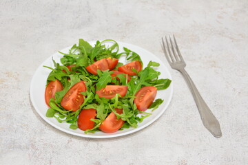 Fresh Arugula and Tomato Salad on a White Plate with a Fork