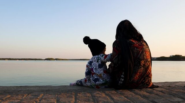 parent and kid enjoying quiet evening by calm lake