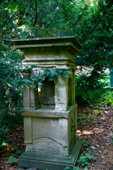 sehr alter Grabstein mit einer großen Öffnung für Kerzen oder Geschenke auf einem Friedhof in Ulm © Blende8