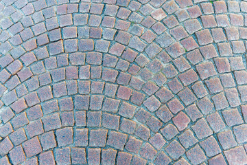 Full frame macro texture of rounded, reddish-brown cobblestone paving