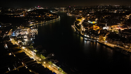 Fototapeta premium Porto at Night from Drone – Illuminated Riverside, Historic Cityscape, Douro River Lights and Old Town Architecture Captured in Stunning Aerial View. Portugal Aerial