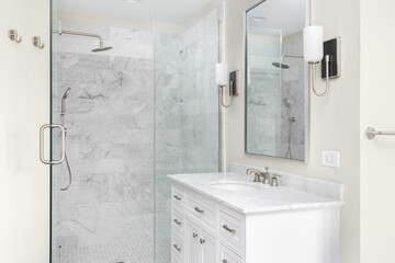 A bathroom with a white cabinet, marble countertop, and a shower with marble subway tiles.