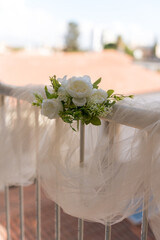 Fototapeta premium Decoration with white flowers on a railing at an outdoor venue in bright sunlight during a wedding ceremony setup