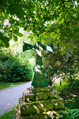 schönes Eisenkreuz im Schatten eines Baumes auf einem Friedhof in Ulm © Blende8