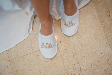 Bridal slippers worn by a bride at a wedding in a venue with light-colored flooring