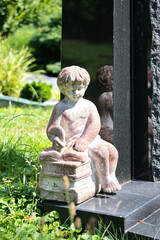 ein kleiner junge sitzt neben einem Grabstein und liest in einem Buch auf einem Friedhof in Ulm