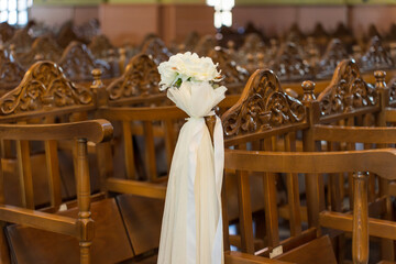 Decorative chairs with flower arrangements during a wedding event inside a community hall