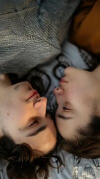 A young couple lying on a bed and looking at each other with affection.