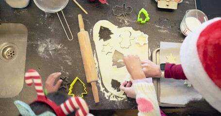Bakers are pressing cookie shapes into dough after girl is selecting green cutter for holiday batch - Powered by Adobe
