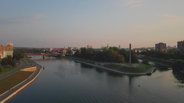 Aerial evening view of Orel city in Russia with river, Strelka, main buildings, churches and roads. Beautiful cityscape with lights reflecting on water at sunset, showing urban architecture, skyline.