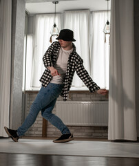 Young guy in a dancing pose on a white background. Modern dance in a plaid shirt. Sports plastic...