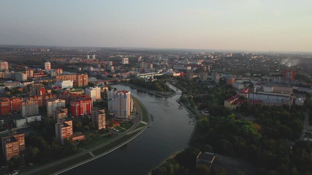 Aerial evening view of Orel city in Russia with river, Strelka, main buildings, churches and roads. Beautiful cityscape with lights reflecting on water at sunset, showing urban architecture, skyline.