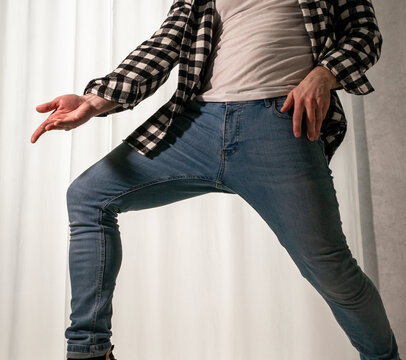Young guy in a dancing pose on a white background. Modern dance in a plaid shirt. Sports plastic movements of arms and legs and body.