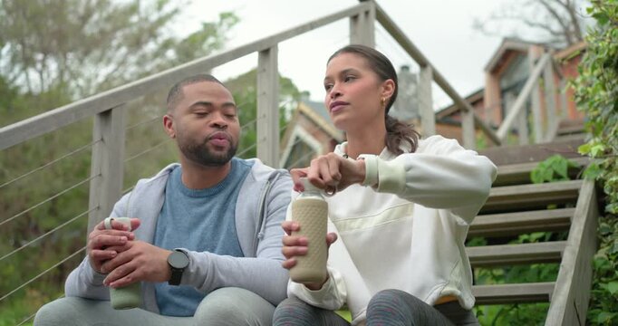 Diverse friends following smartwatch demo, opening bottles and hydrating on wooden deck steps