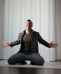 Young guy in a dancing pose on a white background. Modern dance in a plaid shirt. Sports plastic movements of arms and legs and body.