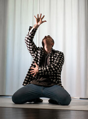 Young guy in a dancing pose on a white background. Modern dance in a plaid shirt. Sports plastic movements of arms and legs and body.