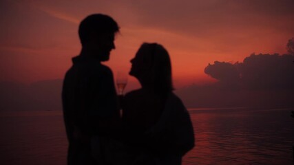A mature couple celebrates their love at a breathtaking sunset, embracing intimately by the ocean. They raise champagne glasses, creating a truly unforgettable moment.