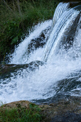 Small cascading waterfall flowing over rocks in natural setting vertical