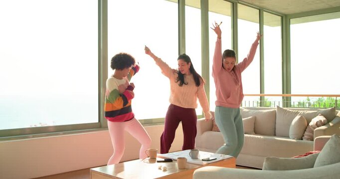 Beat picking up, three women singing into mics, dancing steps around coffee table in living room