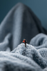 A figurine of a miniature mountain climber, set on a soft fleece surface that mimics a snow-covered landscape
