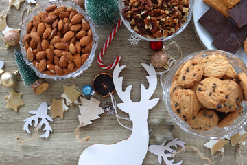 Various Christmas decorations, cookies, chocolate and nuts on wooden background. Flat lay.