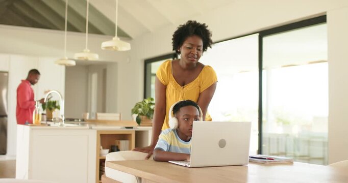 African American family reacting to ping father pouring juice as mother guiding son at dining table