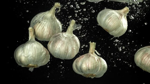 The heads of fresh garlic fall under the water. Filmed on a high-speed camera at 1000 fps. High quality FullHD footage
