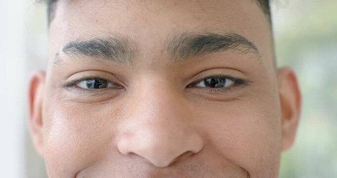Male lifting eyebrows after locking gaze with camera, smiling and squinting near window