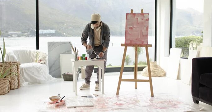 After laying sheet, artist is mixing paints and testing strokes to refine color near lake view