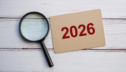 Magnifying Glass Focusing on Red 2026 Text on Cardboard Paper for Future Planning or Forecast Concept