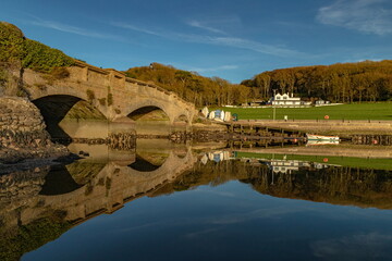 Axmouth Bridge reflected on the water of river Axe near town of Seaton, Devon