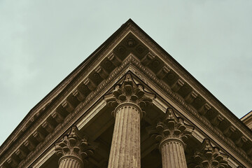 Ornate corinthian colonnade viewed from below under overcast sky