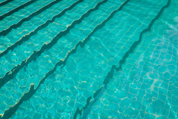 submerged steps in turquoise water of swimming pool with ripples; relaxation and tranquility in summer holiday