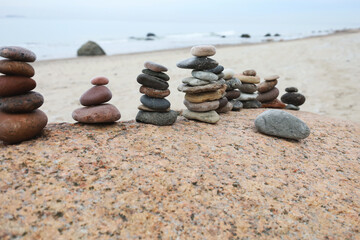 Calm beach sculpture, Peaceful cairns creating tranquil seaside meditation scene, Harmonious stone arrangements on beach evoke relaxation and exploratory leisure activities