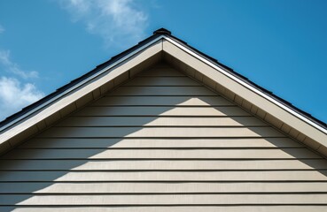 Close up photo of home roof. Modern house exterior with light siding panels and dark roof. Blue sky on background. Architecture construction project.