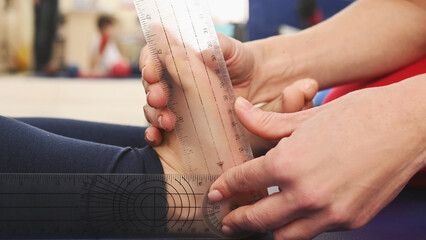 A doctor measures a preschooler's flat feet using a goniometer. Rehabilitation and correction of posture and gait problems in children.