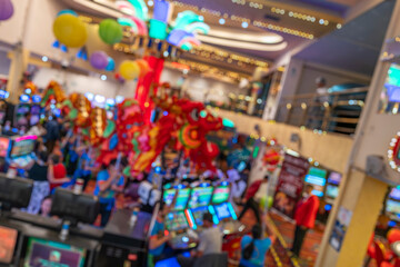 Blurred image of a festive scene in a casino with Chinese dragon dancing, colorful lights, slot machines, and vibrant decor.