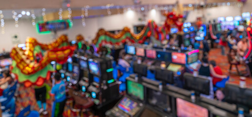 Blurred image of a festive scene in a casino with Chinese dragon dancing, colorful lights, slot machines, and vibrant decor.