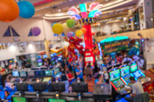Blurred image of a festive scene in a casino with Chinese dragon dancing, colorful lights, slot machines, and vibrant decor.