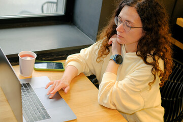 Woman doing remote work using laptop in cafe