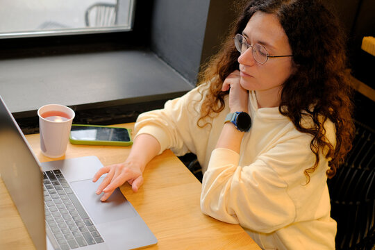 Woman doing remote work using laptop in cafe - Powered by Adobe