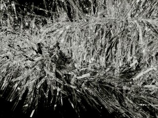 silver tinsel strands pile shiny reflective chaotic dense tangled monochrome abstract close-up texture highlights shadows glittering foil strips