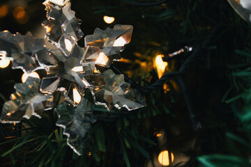 A close-up shot of an ornate cut glass snowflake hanging from a Christmas tree as a luxury xmas...