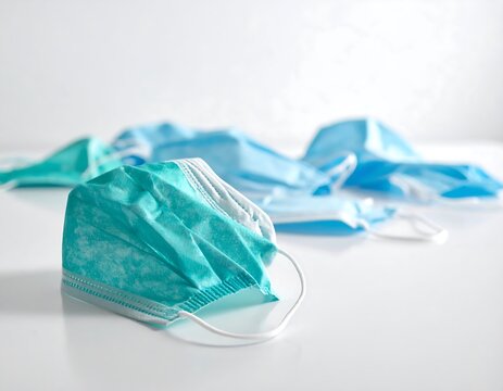 Several light teal and light blue face masks on a white surface