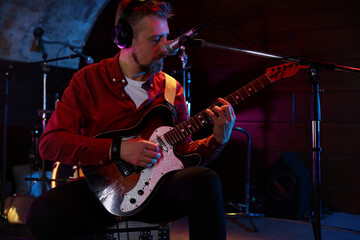 Obraz premium Man in headphones playing electric guitar on stage