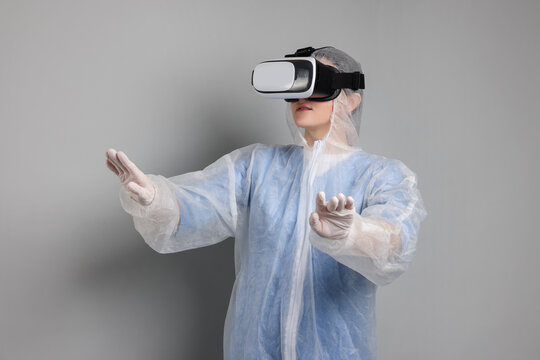 Modern technology. Doctor using virtual reality headset on grey background - Powered by Adobe